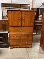 Oak dresser front view showing two-door cabinet and six drawers with brass and wooden handles.