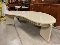 Angled side view showing the table's kidney-shaped top, gold trim, and rectangular legs.