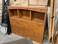 Photo of the single wood bookcase headboard showing three built-in compartments and natural wood finish.