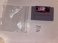 Front view of the SNES game cartridge Magic Sword with plastic zip-lock bag and lot number card.