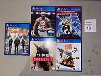 Five PS4 game cases including The Division, EA Sports UFC, Ratchet & Clank (PlayStation Hits), Sniper Contracts 2, Rocket Arena (brand new).