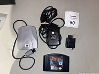 Photo of Nintendo 64 extras including Expansion Pak, power adapter, AV cable, and Turok 2 game cartridge.