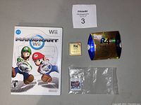 Full lot showing Wii Mario Kart game case, R4 Gold Pro SDHC cartridge and packaging, and Nintendo 3DS Pokémon Y cartridge in plastic bag.
