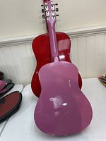 Back view of pink kids acoustic guitar showing scratches