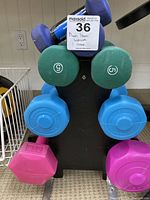 Photo of assorted colored dumbbells (pink, blue, green, purple) on a black dumbbell stand
