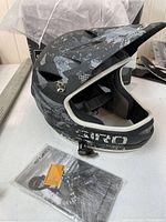 Full face black and grey patterned Giro Remedy helmet with instruction manual visible below it.