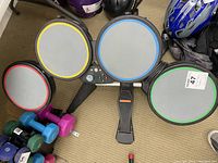 Full top view of the Guitar Hero drum set showing four drum pads with color outlines (yellow, blue, red, green) and the kick pedal beneath.