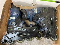 Pair of men's roller blade skates in black and dark blue color, showing adjustable straps, wheels, and boot details. Lot contents displayed clearly.