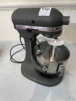 Front-left view of gray KitchenAid ProLine mixer with stainless bowl and wire whip attached