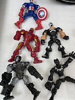 Top-down view of the 5 Marvel superhero action figures arranged on white background including Captain America, Iron Man, War Machine, Black Panther, and Taskmaster.