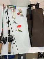 Full lot overview showing two fishing rods with reels, a collection of lures and tackle including a bobber, and a pair of brown neoprene full hip waders.