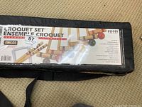 Black fabric carrying case labeled 'Croquet Set Ensemble Croquet' with product information.