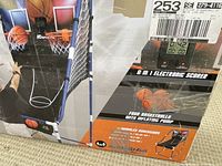 Photo of the product box showing assembled portable basketball shooting game with dual hoops, electronic scorer, and basketballs.
