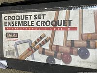 Label on croquet set carrying case indicating 'Croquet Set Ensemble Croquet' with images of mallets and balls.