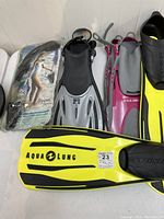 Photo showing all fins and the snorkel in packaging, including Aqua Lung adult fins, US Diver kids fins in black/grey and pink.