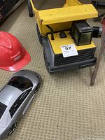 Photo showing Tonka toy dump truck, Lamborghini Murcielago toy car, and red fire helmet positioned on carpeted floor.