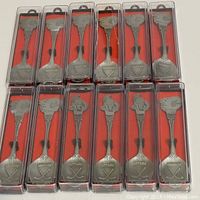 12 hockey collectible spoons, 9 Calgary Flames and 3 Ottawa Senators, individually packaged in plastic cases with red background, silver-tone metal with engraved logos and crossed hockey sticks