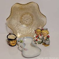 All five items arranged together on a white background: two Dutch figurines, small Toby jug, Nippon dish, and carnival glass leaf bowl
