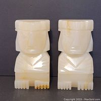 Front view of the pair of carved marble bookends showing symmetrical stylized human figure design