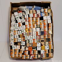 Top view of many boxed electronic tubes in a large box, mostly orange and white boxes with visible brand names and handwritten labels.