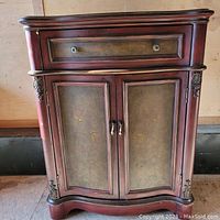 Front view of the antique red coffret cabinet showing two doors with decorative panels and one drawer above.