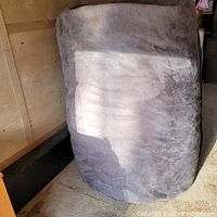 Large grey bean bag chair standing upright, showing size and fabric texture.