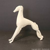 White resin stylized dog figurine on black surface and background, showing full side profile