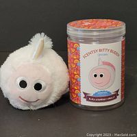 Plush unicorn Bitty Buddy next to scented wax container showing front labeling