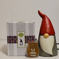 Photo of white striped box labeled Scentsy Christmas Gnome, with a Scentsy Chillin & Grillin wax bar in front and part of the gnome warmer visible beside it.