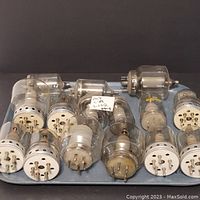 Overview of vintage vacuum tubes displayed on a tray showing the bases and pins, indicating type and condition.