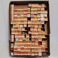 Large assortment of vacuum tubes in original GE branded orange and white boxes arranged tightly in a cardboard box.