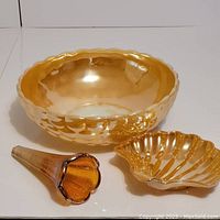 Lot of three vintage glass pieces: large peach Hocking bowl, marigold crackle Carnival bud vase, and sea shell luster bowl on white background.