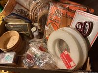 Overview of craft supplies from above showing baskets, small glitter jar, wooden hoops, Styrofoam wreaths, scissors set, and macramé kits