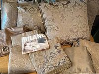 Full lot of bedding and curtains from Milano collection displayed on a table showing damask pattern items and packaging.