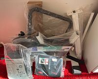 Unassembled Healthware exercise bike frame parts in plastic bags on red carpet