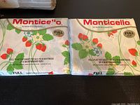 Two Monticello brand full flat top sheets with strawberry and floral prints, packaged in original plastic wrap, unopened.