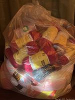 Large bag filled with many skeins of yarn in red, pink, and white colors.