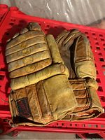Pair of vintage leather hockey gloves placed on a red plastic surface to show overall condition and fitment.