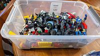 Photo of plastic container filled with varied action figures and building bricks showing colors and mixture of items.