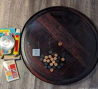 Top-down photo of wooden Crokinole board showing playing pieces with vintage roulette game and pocket Scrabble placed to the side.