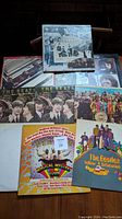 Seven Beatles album covers arranged on table, one propped upright