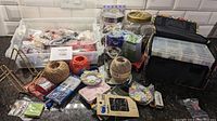 Overview of assorted crafting supplies including containers, balls of string, button cards, and a small carry case