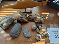 Overview photo of collection including rocks, arrowhead, fossils, and two wood dolphin sculptures, displayed on wooden surface.