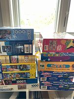 Stack of unopened puzzle boxes showing different brands and puzzle sizes from 48 pieces to 1000 pieces.