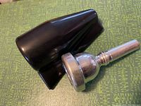 Mouthpiece and protective cover placed on a patterned surface, showing the profile and details of the mouthpiece and the cover alongside.