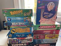 Photo showing stacked boxed games including Yahtzee Jr., Old MacDonald Lotto, Angry Birds Knock on Wood, Don't Make Me Laugh Jr., Pop n Go, Connect 4 and Sudoku 2.
