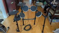 Full view of the Alesis DM Lite electronic drum kit including drum pads, cymbal pad, drum module, and stand on a wood floor.