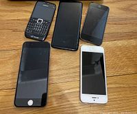 Front view showing five smartphones: Nokia with physical keyboard, three iPhones with home buttons, one Samsung Galaxy smartphone.