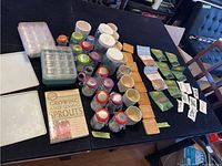 Overview of sprouting kit showing jars with colored lids, wooden lids, seed packets, trays and the guide book.