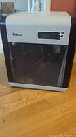 Front view of the XYZPrinting da Vinci 1.0 3D printer showing white and black exterior with transparent door and visible interior printing assembly.
